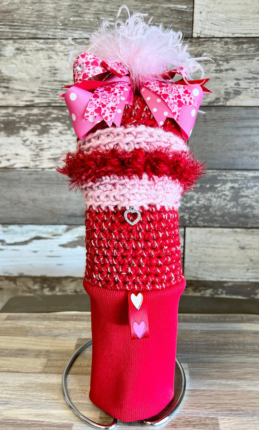 Knitted head cover titled Dream Lover featuring a red sock with a bow, jewelry, pink bow with hearts, and a red label. Handcrafted and one of a kind.