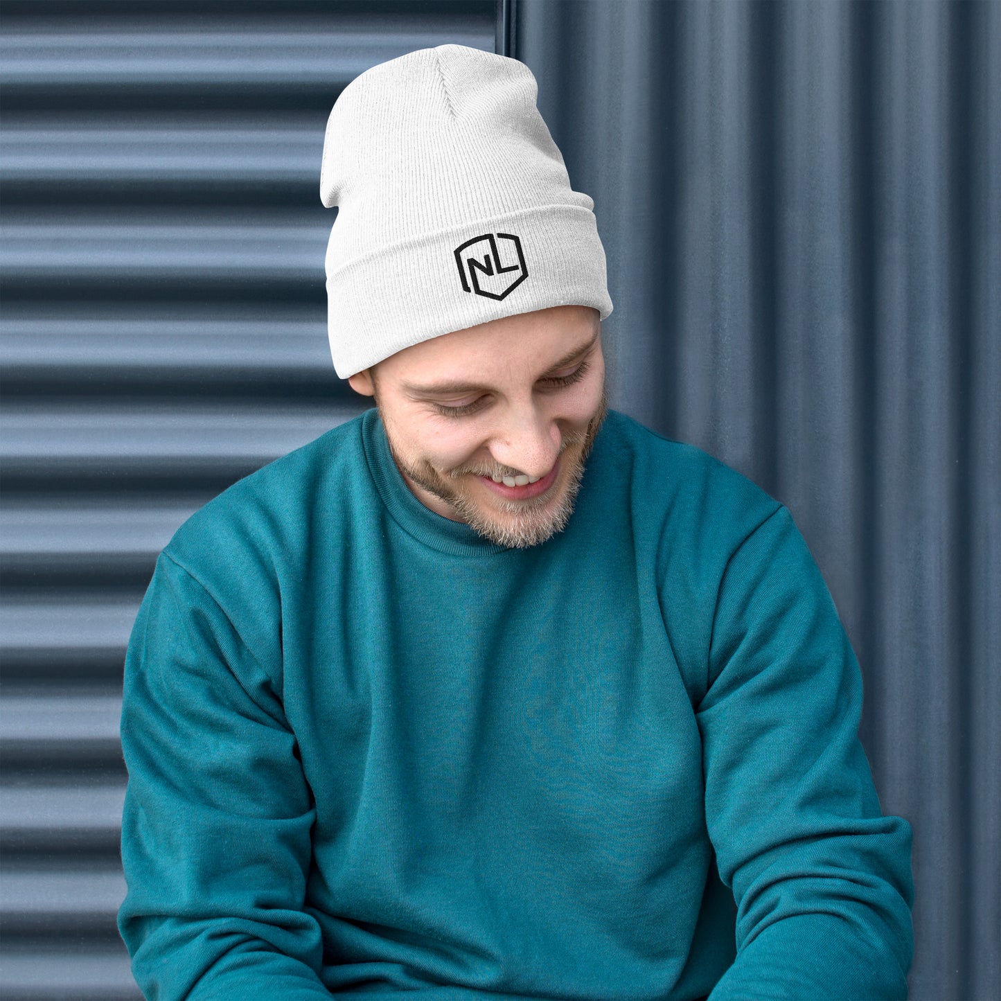 A man in a white beanie and hoodie, showcasing a form-fitting, embroidered NEVR LOOZ hat - Beanie. Made of 60% cotton, 40% acrylic for cozy warmth. On-demand production for sustainability.